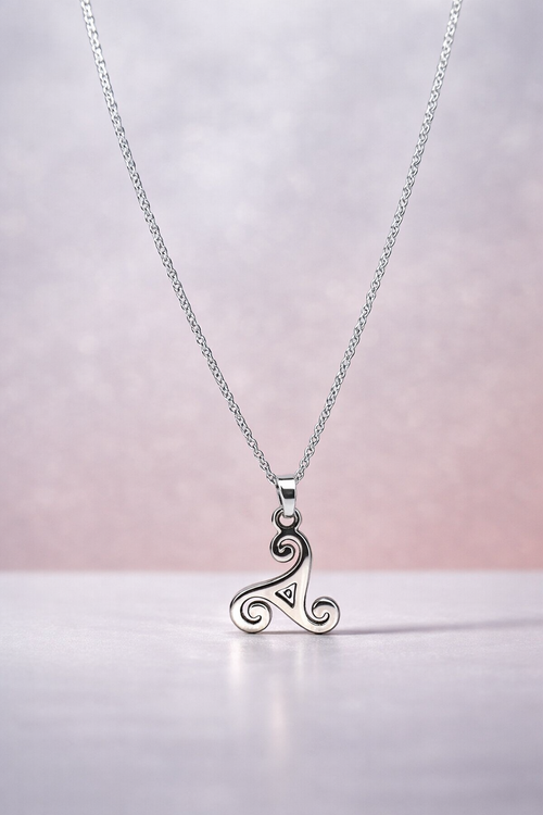 Silver necklace with a triskele pendant on a light pink background