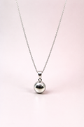 Silver necklace with a round ball pendant on a light pink background