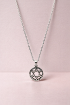 Silver necklace with a Star of David pendant on a pink background