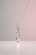 Silver necklace with a detailed marquise pendant on a light pink background