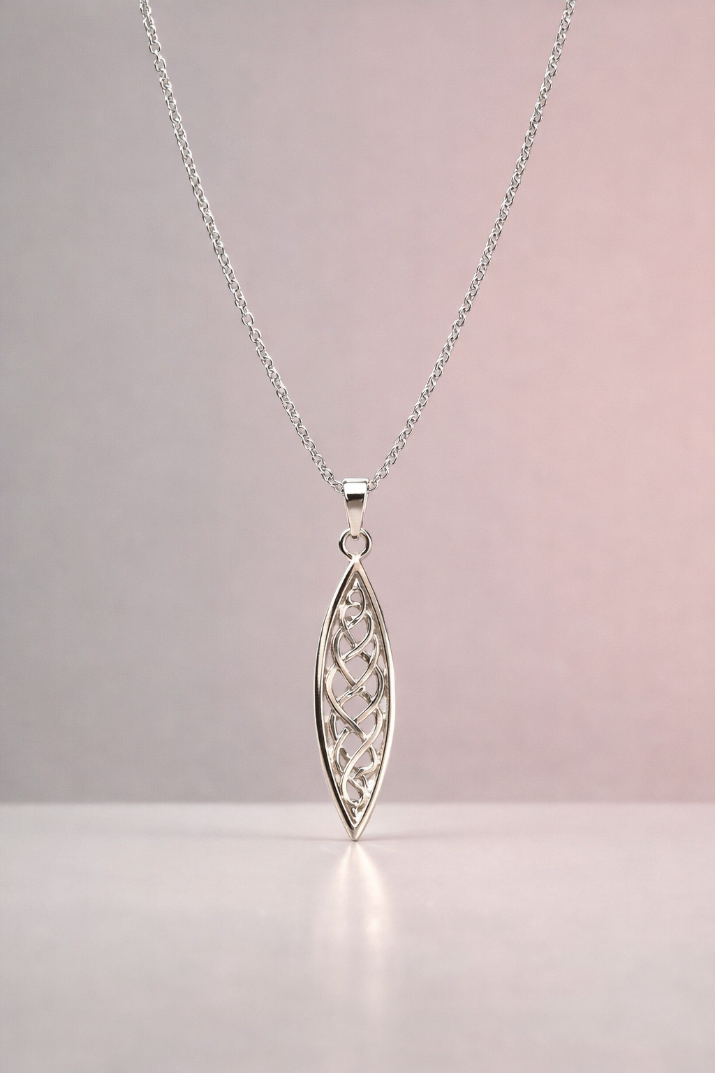 Silver necklace with a detailed marquise pendant on a light pink background