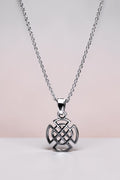 Silver necklace with a Celtic knot pendant on a light pink background