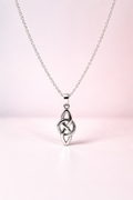 Silver Celtic knot pendant on a chain against a light pink background