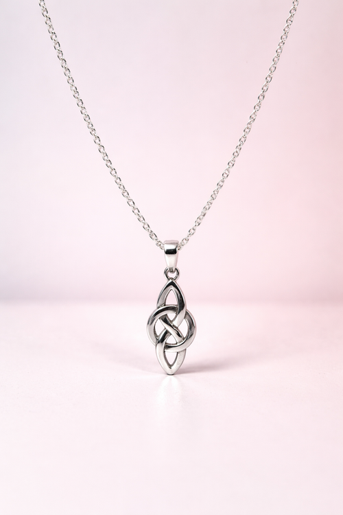 Silver Celtic knot pendant on a chain against a light pink background