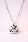 Silver pendant necklace with intricate design on a light pink background