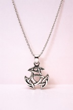 Silver pendant necklace with intricate design on a light pink background