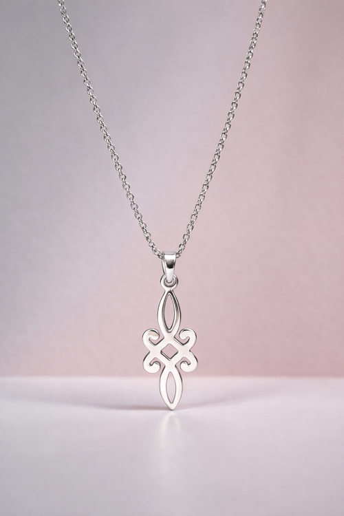 Silver necklace with a decorative pendant on a light pink background