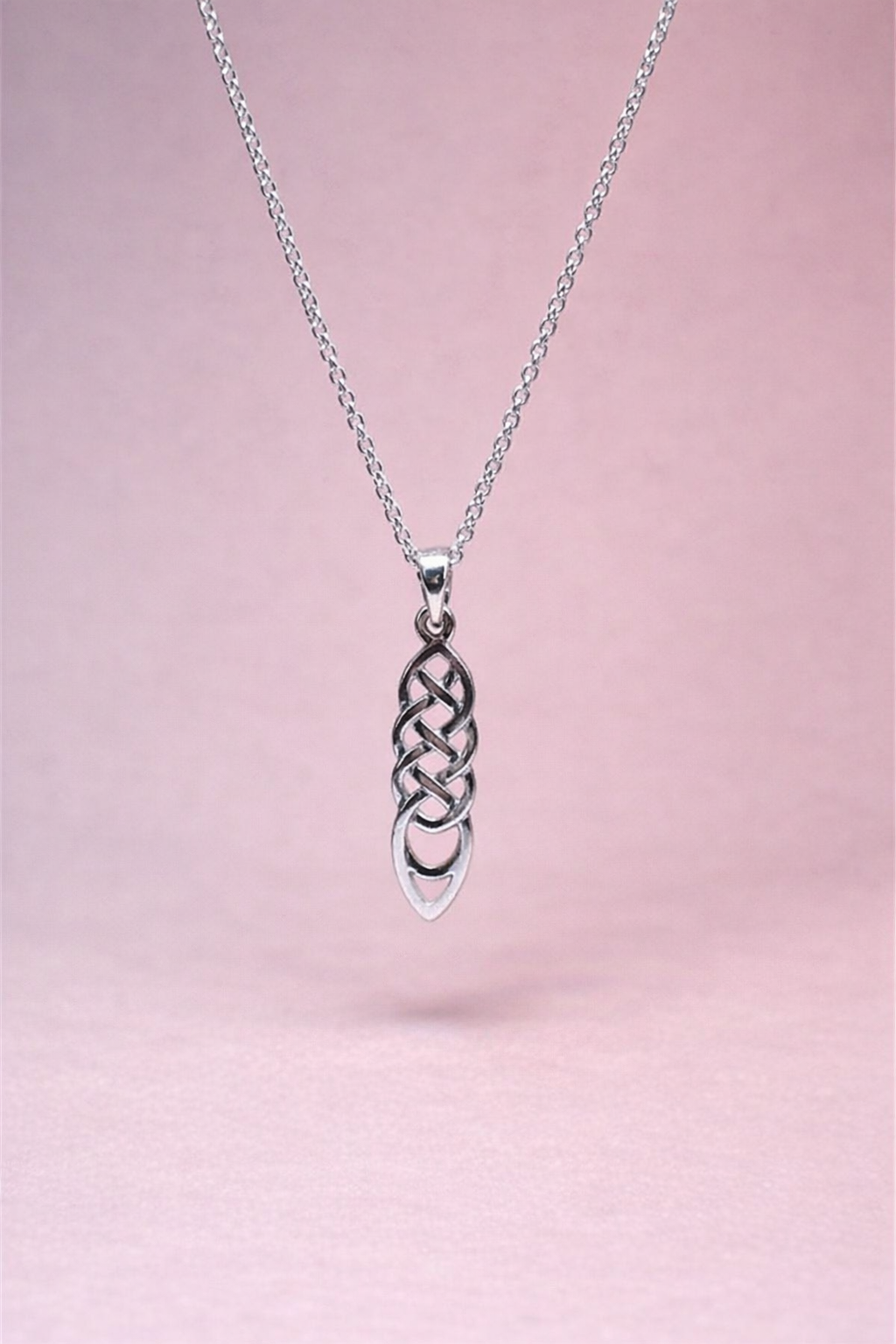 Silver necklace with a Celtic knot pendant on a pink background