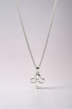 Silver necklace with a clover-shaped pendant on a light gray background