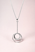 Silver necklace with a crescent circle pendant on a light pink background