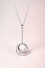 Silver necklace with a crescent circle pendant on a light pink background