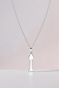 Silver necklace with a unique pendant on a light pink background
