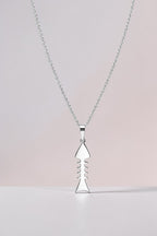Silver necklace with a unique pendant on a light pink background