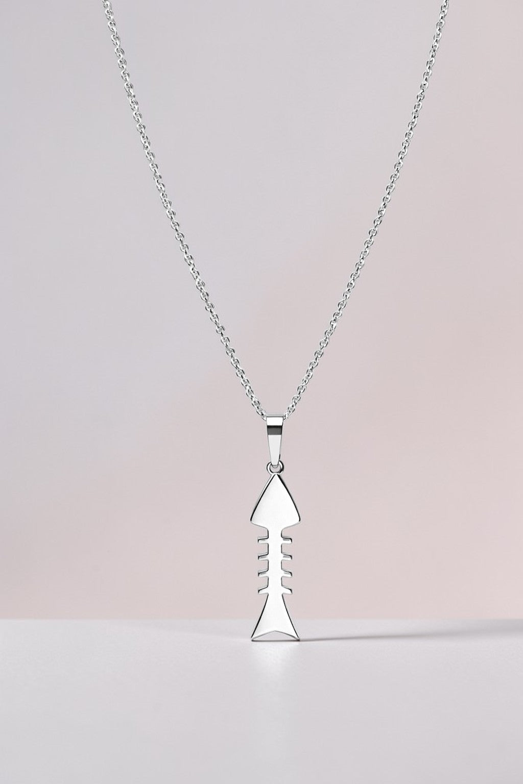 Silver necklace with a unique pendant on a light pink background