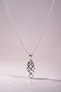 Silver necklace with a Celtic knot pendant on a light pink background