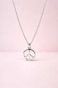 Silver peace sign necklace on a pink background