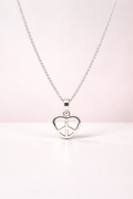 Silver necklace with a heart-shaped peace pendant on a light pink background