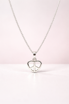 Silver necklace with a heart-shaped peace pendant on a light pink background